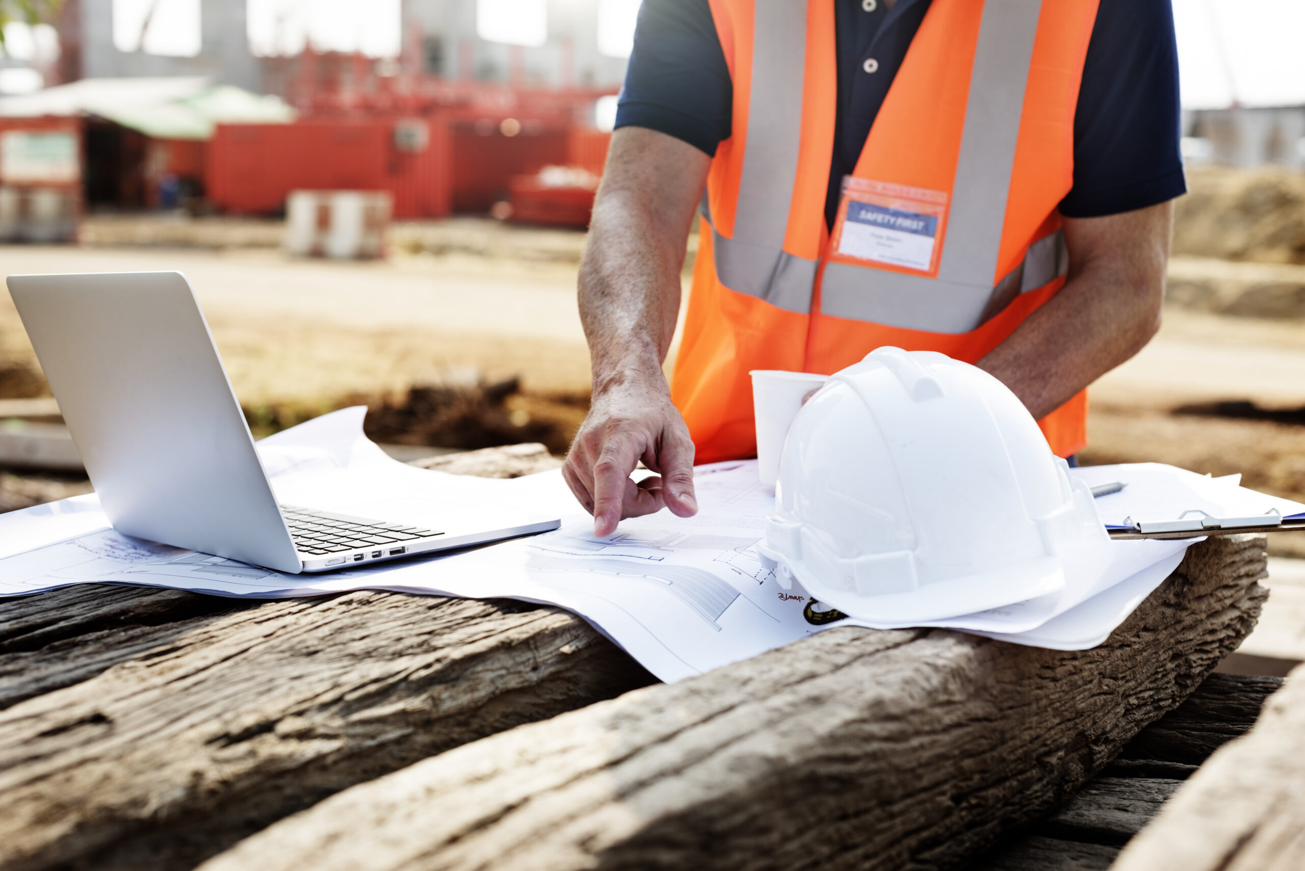 closeup of contractor in construction site pointing at plan on wooden sleeper